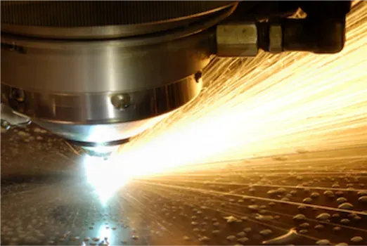 A laser cutting head burning through sheet metal and throwing bright sparks — machine shop and manufacturing insurance in Kansas
