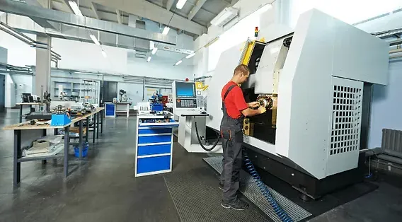 A machinist loading a part at a CNC turning center inside a clean machining facility