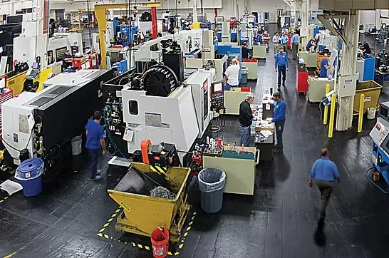 An overhead view of a machine shop floor with machining centers, work cells, and staff at work
