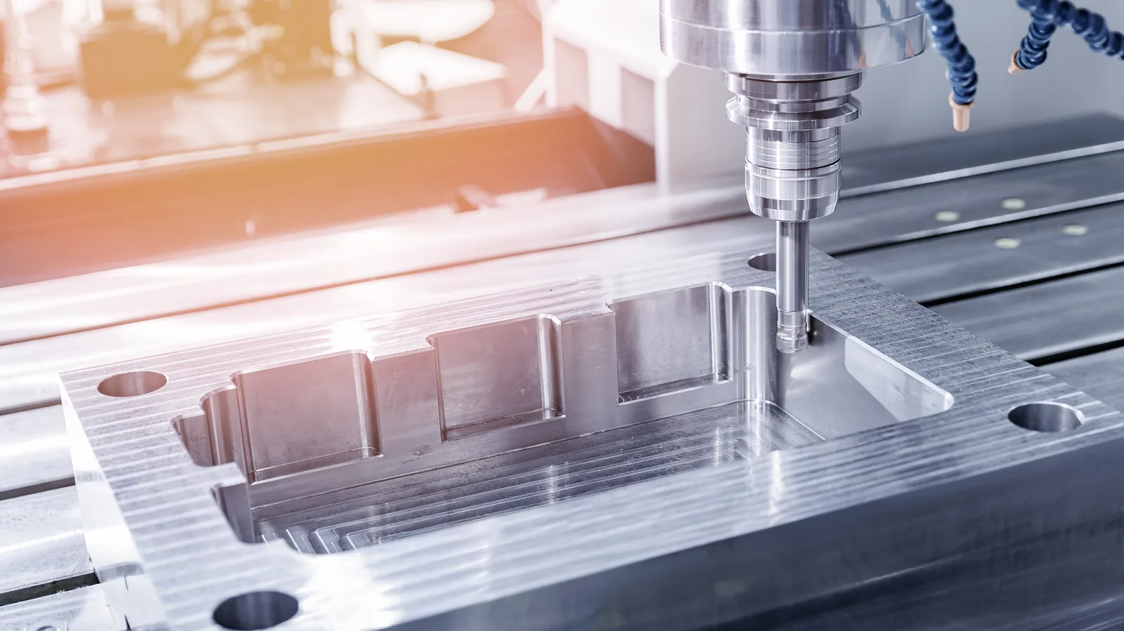 A stepped pocket being machined into a metal plate held on a slotted machine bed